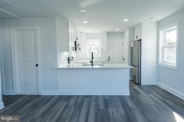 122 Roselawn Rd, Annapolis, MD 21403 - kitchen with white cabinetry, a peninsula, stainless steel appliances, dark wood-style flooring, and light countertops