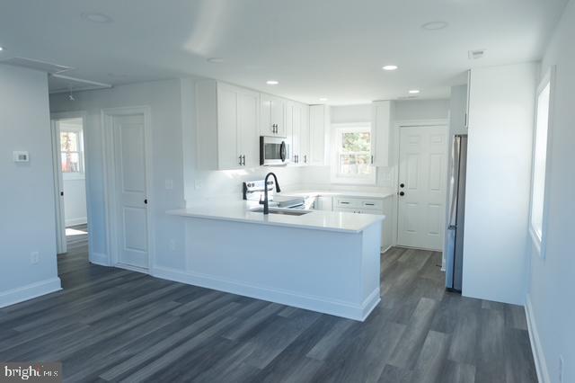 122 Roselawn Rd, Annapolis, MD 21403 - kitchen featuring appliances with stainless steel finishes, a peninsula, dark wood-style flooring, white cabinetry, and light countertops