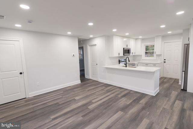 122 Roselawn Rd, Annapolis, MD 21403 - kitchen with stainless steel appliances, white cabinets, a peninsula, dark wood-type flooring, and light countertops