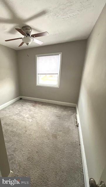 carpeted spare room with ceiling fan