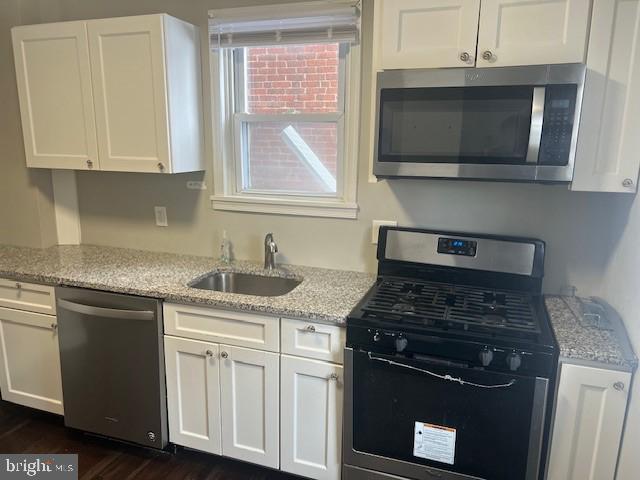 kitchen featuring light stone counters, sink, white cabinets, and appliances with stainless steel finishes