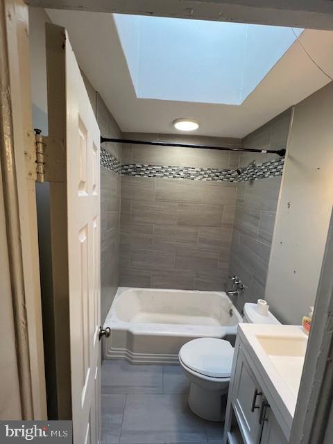 full bathroom featuring toilet, vanity, a skylight, and tiled shower / bath