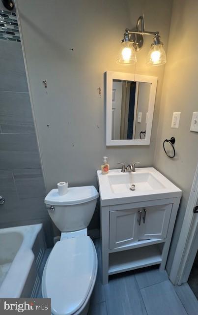 bathroom featuring toilet, vanity, and a tub to relax in