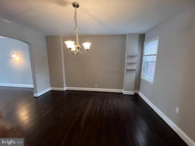 spare room with a chandelier and dark hardwood / wood-style flooring