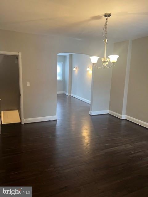 unfurnished room featuring dark wood-type flooring and a chandelier