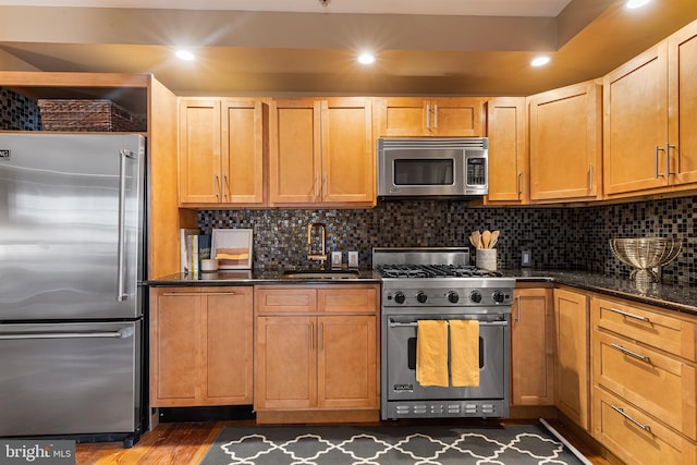 kitchen with dark hardwood / wood-style flooring, backsplash, sink, and high quality appliances