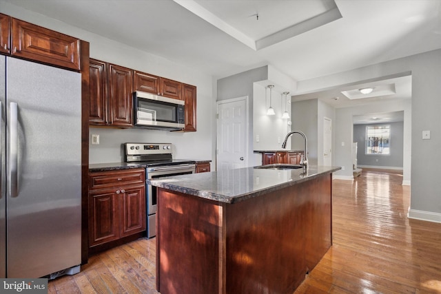 kitchen featuring sink, decorative light fixtures, appliances with stainless steel finishes, and light hardwood / wood-style flooring