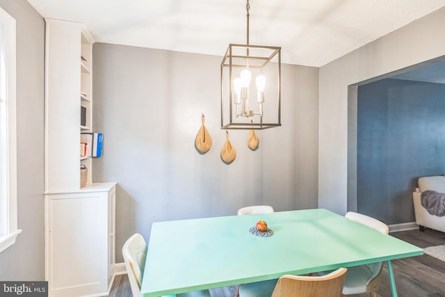 dining area with dark hardwood / wood-style floors and a notable chandelier