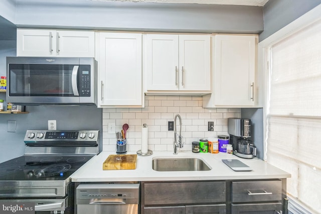 kitchen featuring backsplash, sink, white cabinets, and appliances with stainless steel finishes