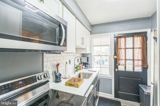 kitchen featuring white cabinetry, sink, wood-type flooring, decorative backsplash, and appliances with stainless steel finishes