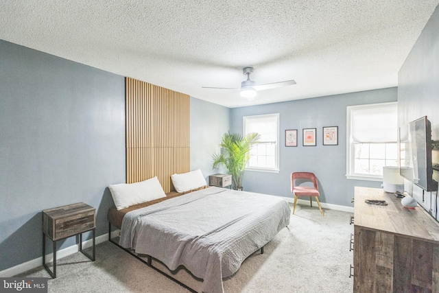 bedroom with a textured ceiling, ceiling fan, and light carpet