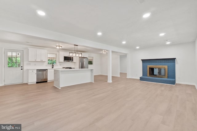 unfurnished living room with sink, light hardwood / wood-style flooring, and a brick fireplace