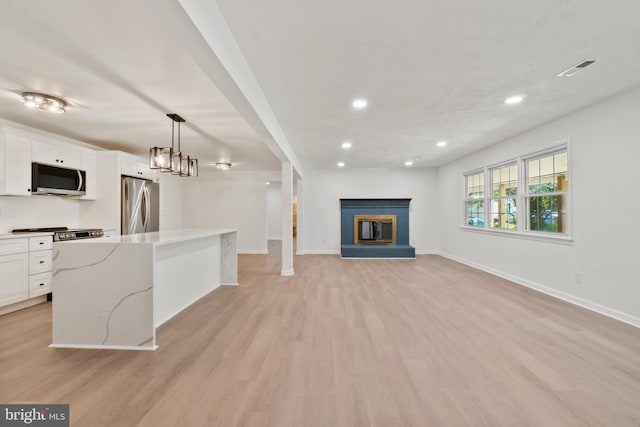 unfurnished living room featuring light hardwood / wood-style floors and a brick fireplace