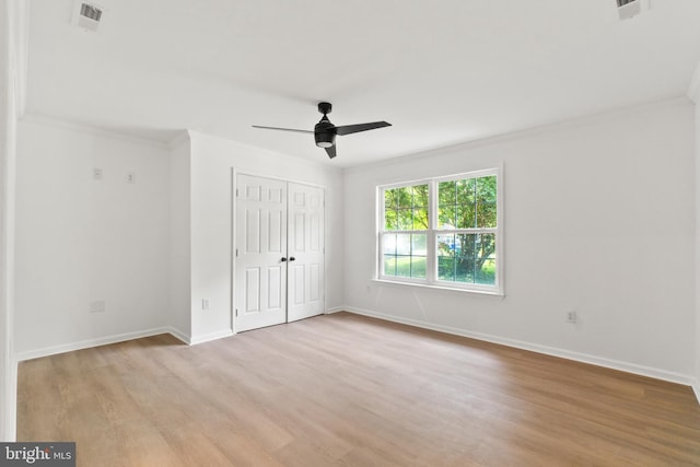 unfurnished bedroom featuring a closet, light hardwood / wood-style flooring, ceiling fan, and ornamental molding