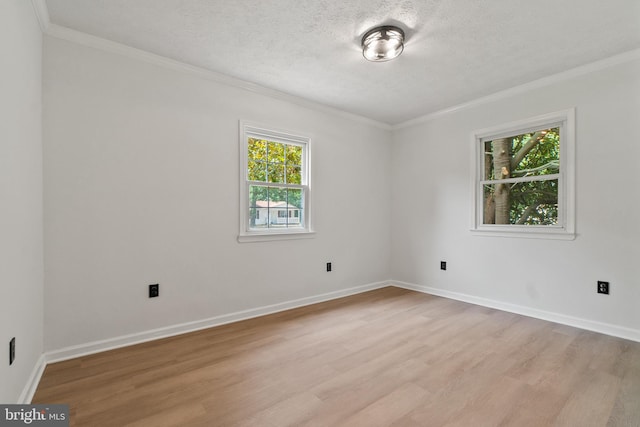 spare room featuring a textured ceiling, light hardwood / wood-style flooring, a wealth of natural light, and ornamental molding