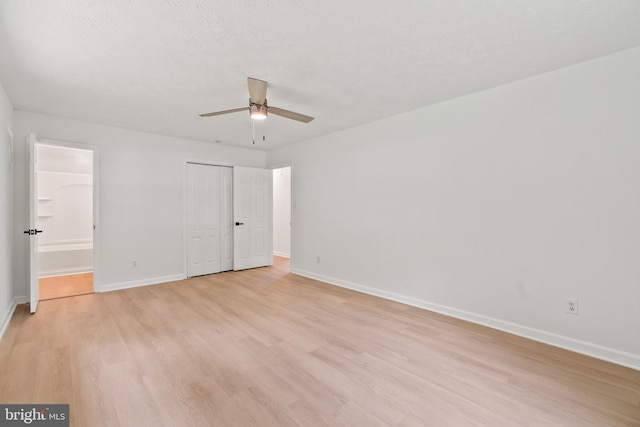 unfurnished bedroom featuring a textured ceiling, light hardwood / wood-style floors, ensuite bath, and ceiling fan