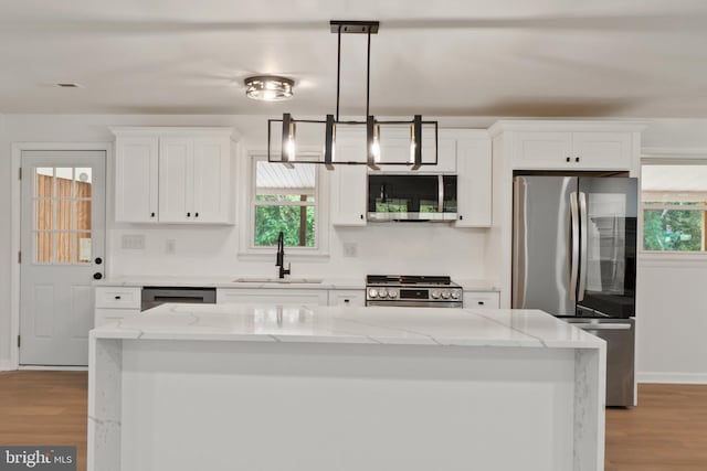 kitchen featuring light stone countertops, sink, stainless steel appliances, and plenty of natural light