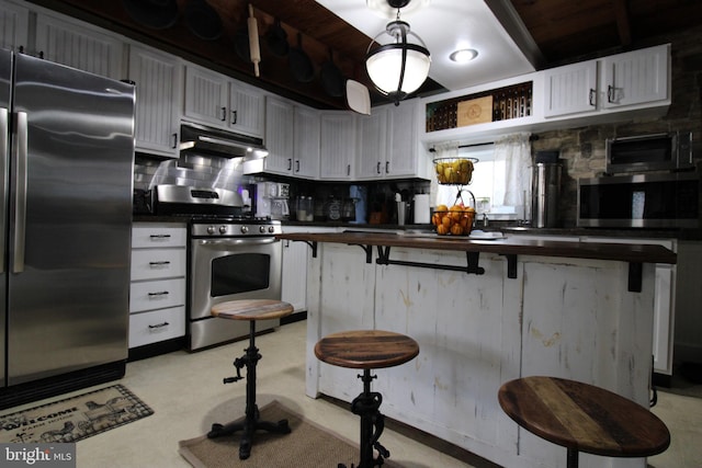 kitchen with butcher block countertops, a breakfast bar, white cabinets, and stainless steel appliances