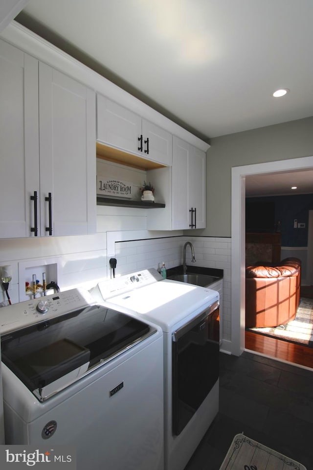 washroom with washing machine and dryer, sink, cabinets, and dark hardwood / wood-style floors