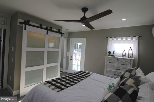 bedroom featuring ceiling fan, a barn door, and access to exterior