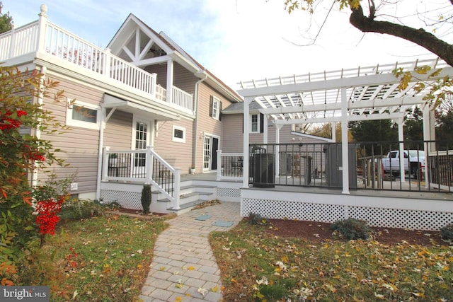 back of house with a balcony, a pergola, and a wooden deck