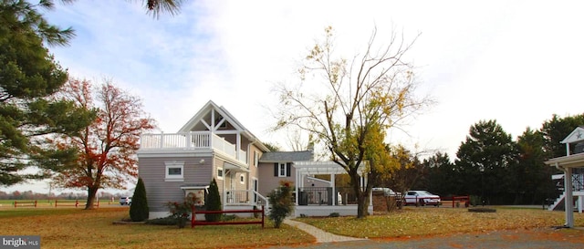 view of front facade with a pergola, a balcony, and a front lawn