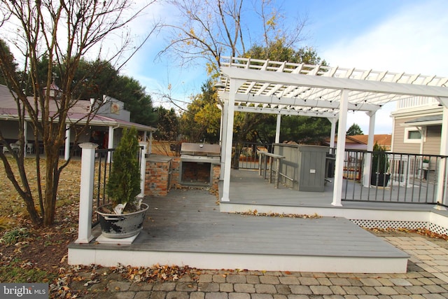 view of patio featuring exterior bar, a pergola, a deck, and exterior kitchen