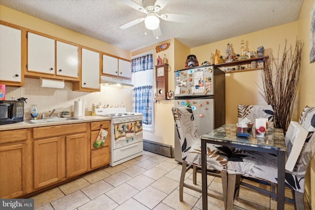 kitchen featuring white range oven, white cabinetry, stainless steel refrigerator, decorative backsplash, and sink