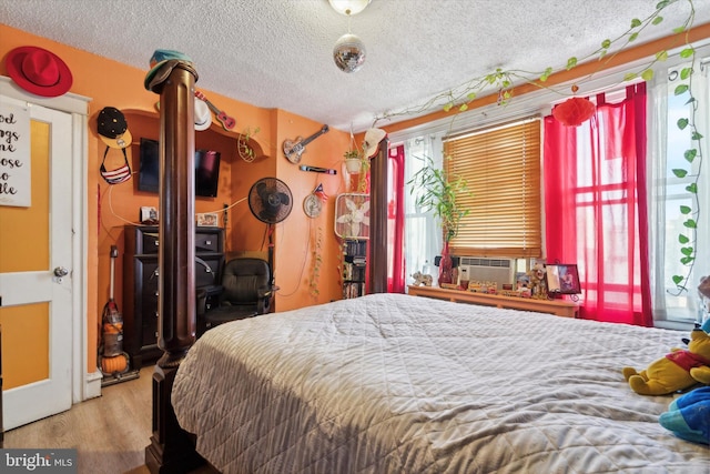 bedroom featuring a textured ceiling, cooling unit, and light hardwood / wood-style flooring