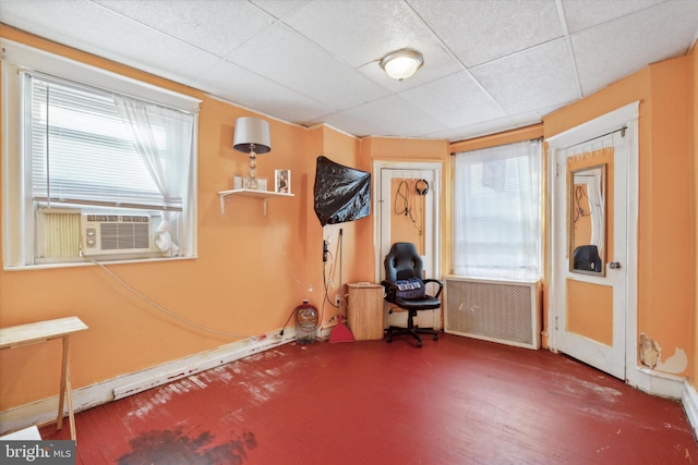 workout area featuring a wealth of natural light, a paneled ceiling, cooling unit, and radiator