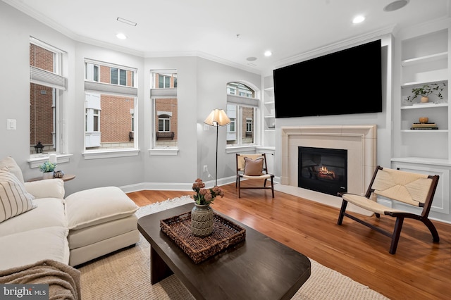 living room with ornamental molding, built in features, a wealth of natural light, and hardwood / wood-style flooring