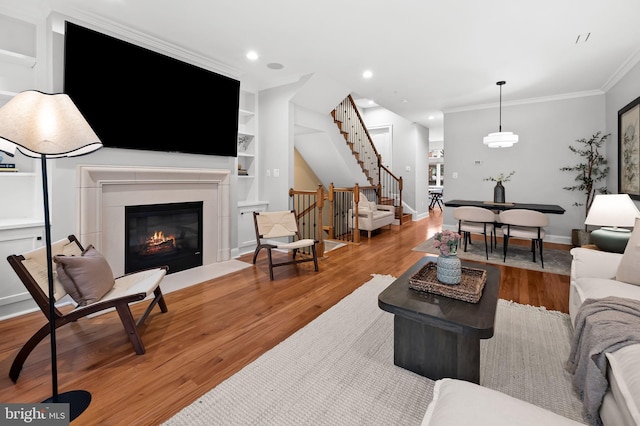 living room featuring crown molding, hardwood / wood-style flooring, and built in features