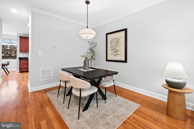 dining space featuring light hardwood / wood-style floors and crown molding