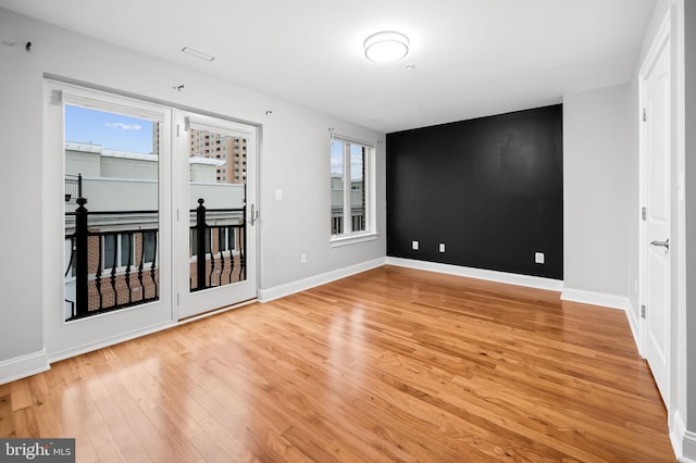 empty room with hardwood / wood-style flooring and plenty of natural light