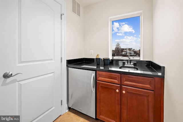 bar featuring stainless steel refrigerator and sink