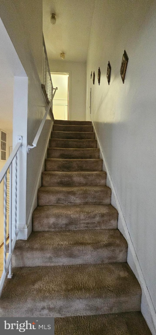 stairs featuring carpet and a textured ceiling