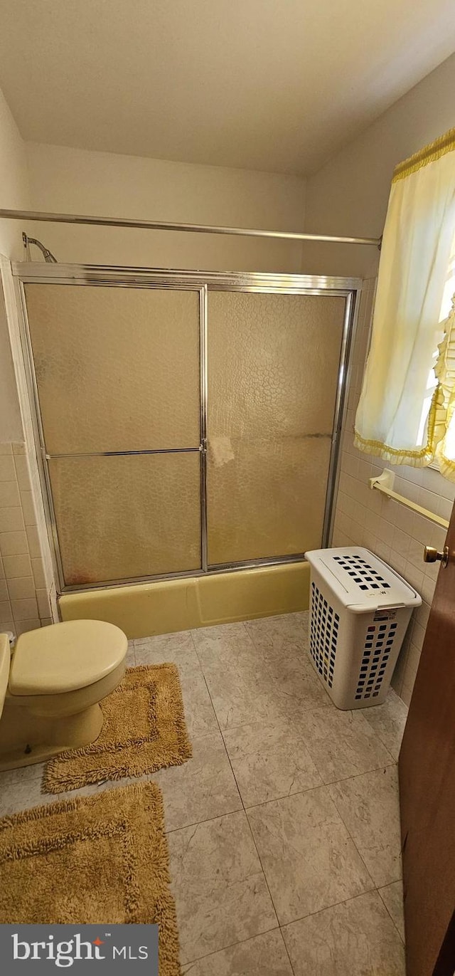 bathroom featuring tile patterned floors, toilet, and a shower with door