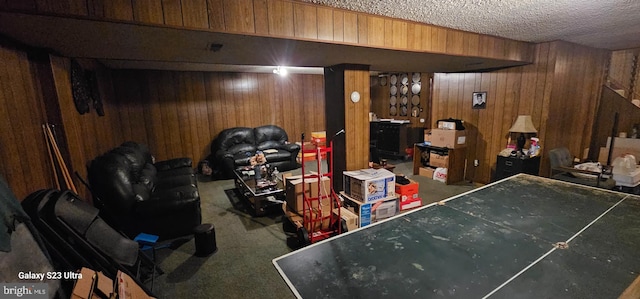 basement featuring wooden walls, carpet floors, and a textured ceiling