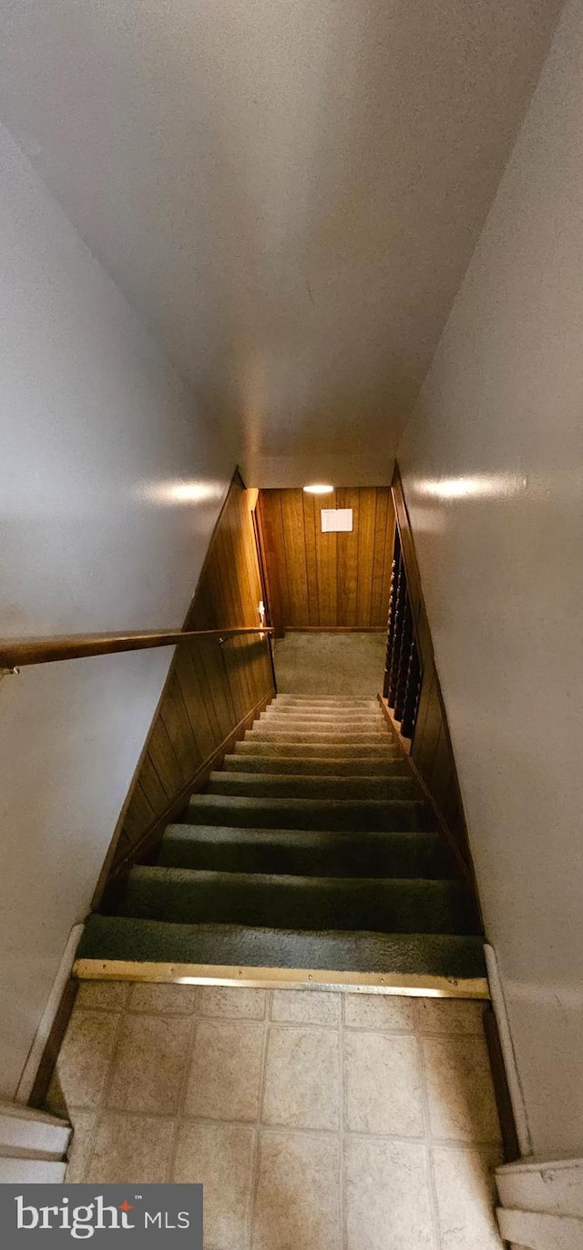 staircase featuring wooden walls