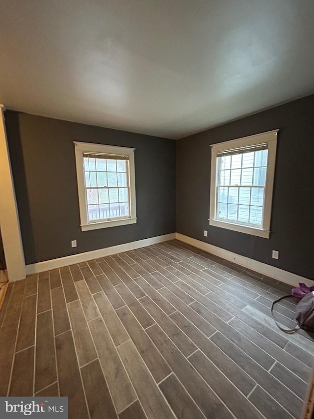 spare room with a wealth of natural light and dark wood-type flooring