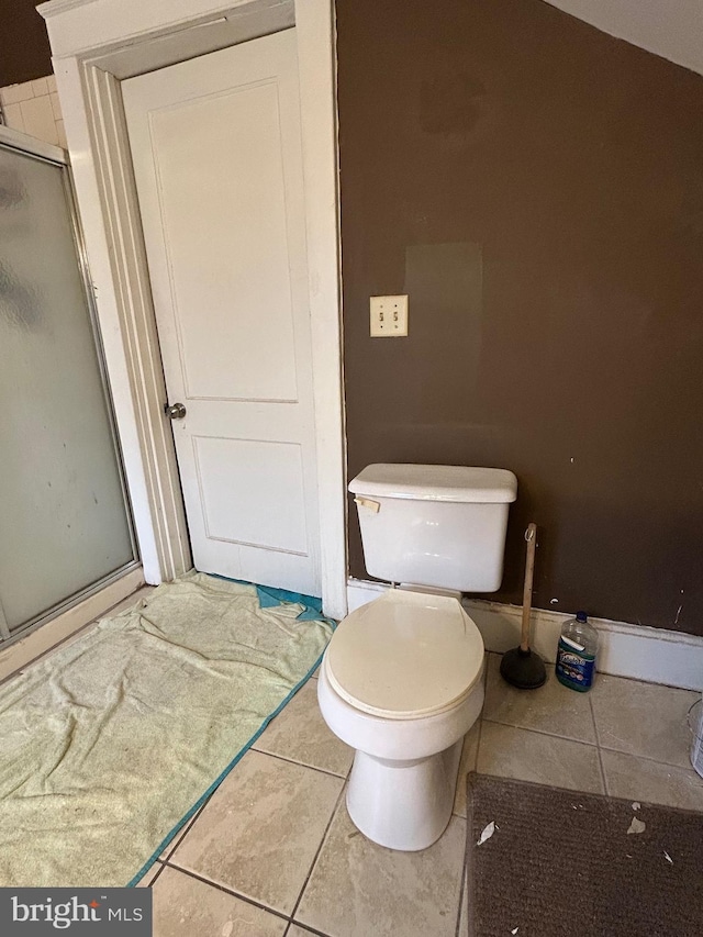 bathroom with tile patterned flooring, toilet, and an enclosed shower