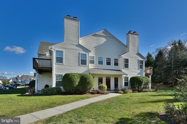 view of front facade with a front lawn and a balcony