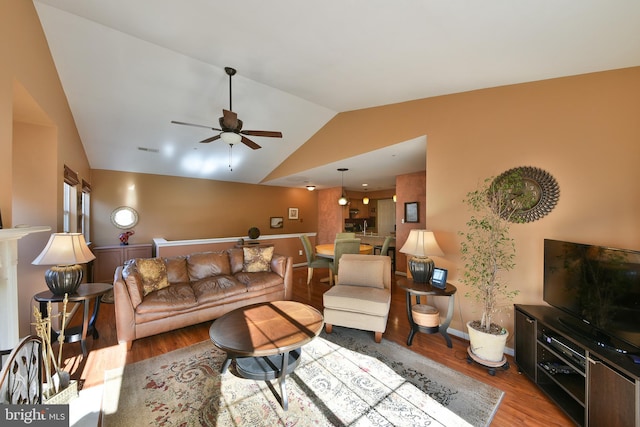 living room with ceiling fan, light hardwood / wood-style flooring, and vaulted ceiling