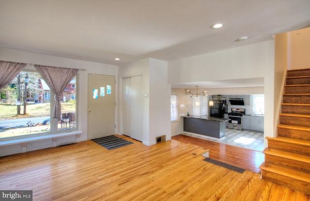 entryway with light wood-type flooring and an inviting chandelier