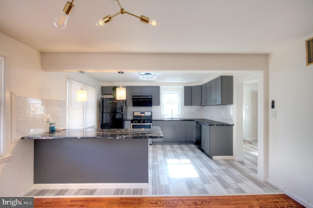 kitchen featuring kitchen peninsula, hanging light fixtures, light hardwood / wood-style flooring, and appliances with stainless steel finishes