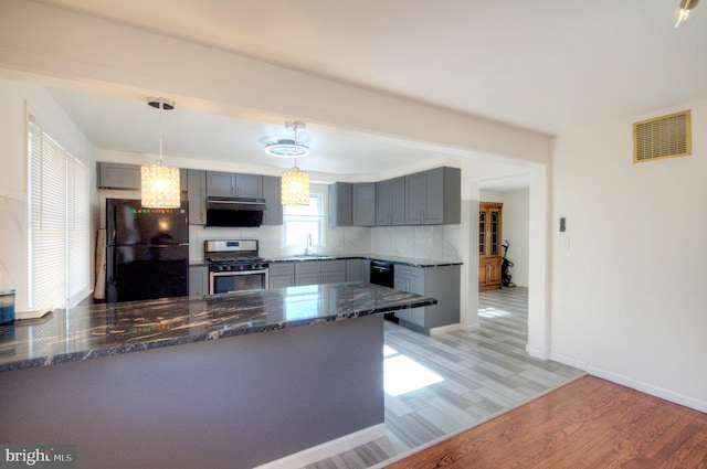 kitchen with stainless steel appliances, pendant lighting, kitchen peninsula, and light wood-type flooring