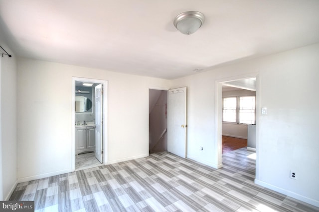 unfurnished bedroom with ensuite bathroom and light wood-type flooring