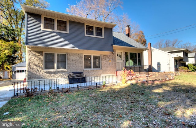 view of front facade featuring a garage, a front lawn, and an outbuilding