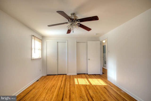 unfurnished bedroom featuring two closets, ceiling fan, and light hardwood / wood-style flooring