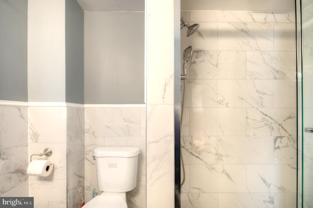 bathroom with tile walls, tiled shower, and toilet